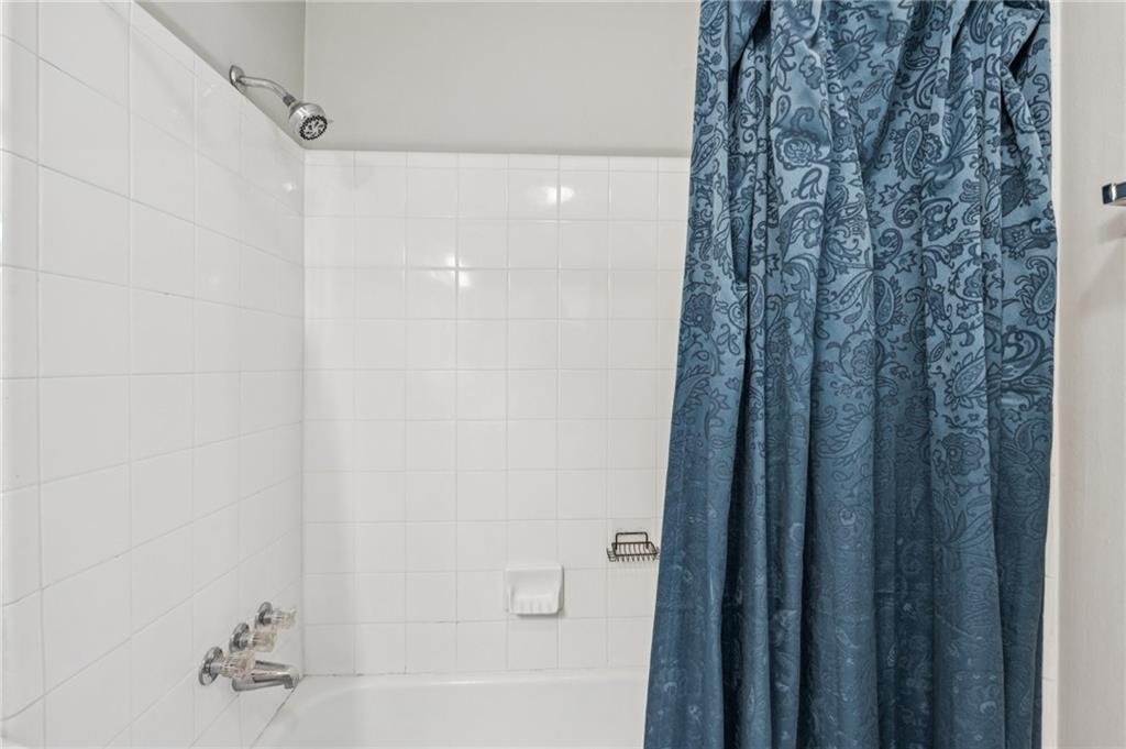 1150 Collier Road Northwest, Unit 16H Atlanta, GA 30318 - Photo 14 of 27 a bathroom with a shower curtain and a bath tub