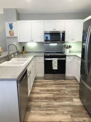 a kitchen with stainless steel appliances granite countertop a sink stove microwave and refrigerator