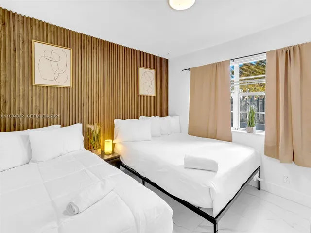 a large white bed sitting in a bedroom next to a window