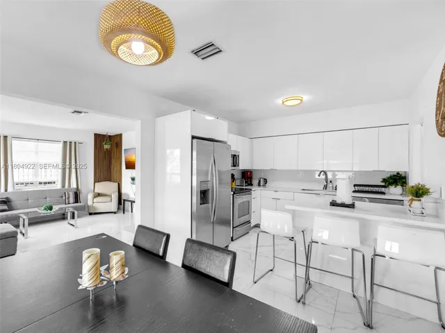 a living room with stainless steel appliances furniture a rug and a view of kitchen