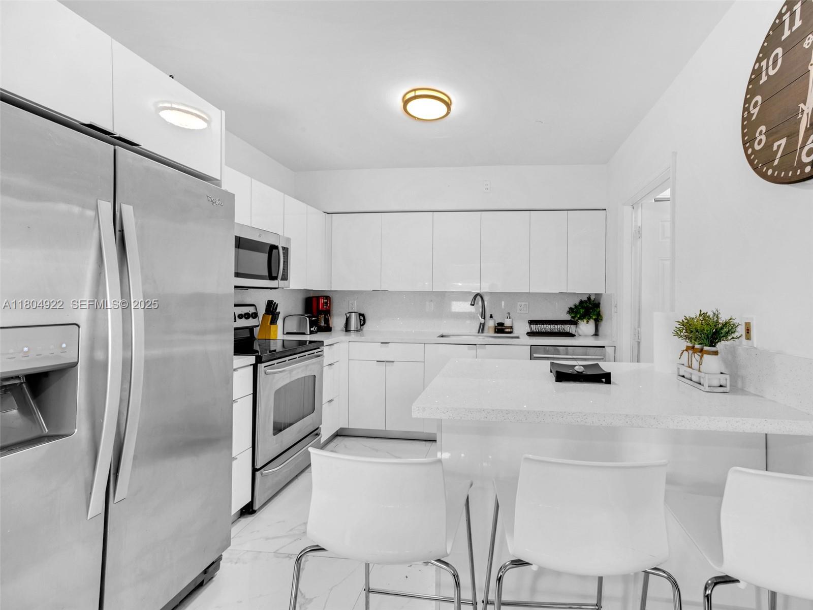 421 West Pembroke Road Hallandale Beach, FL 33009 - Photo 4 of 24 a kitchen with white cabinets and stainless steel appliances