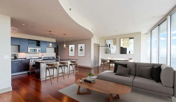a living room with stainless steel appliances furniture and a kitchen view