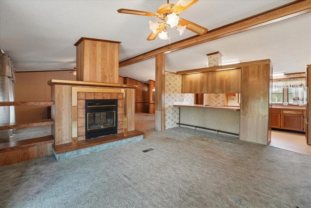 1453 Joyce Road Kaufman, TX 75142 - Photo 22 of 40 Carpeted living area featuring a fireplace with brick surround, built-in shelving, and a ceiling fan