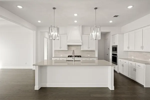 a large kitchen with kitchen island white cabinets and stainless steel appliances