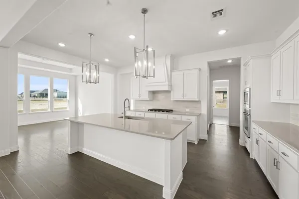a large kitchen with granite countertop a large counter top a sink stainless steel appliances and cabinets