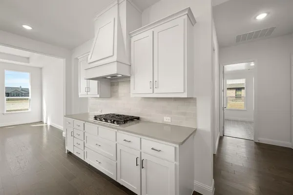a kitchen with granite countertop a stove a sink and white cabinets with wooden floor