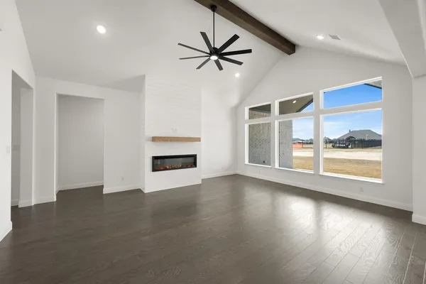 an empty room with wooden floor fan and windows
