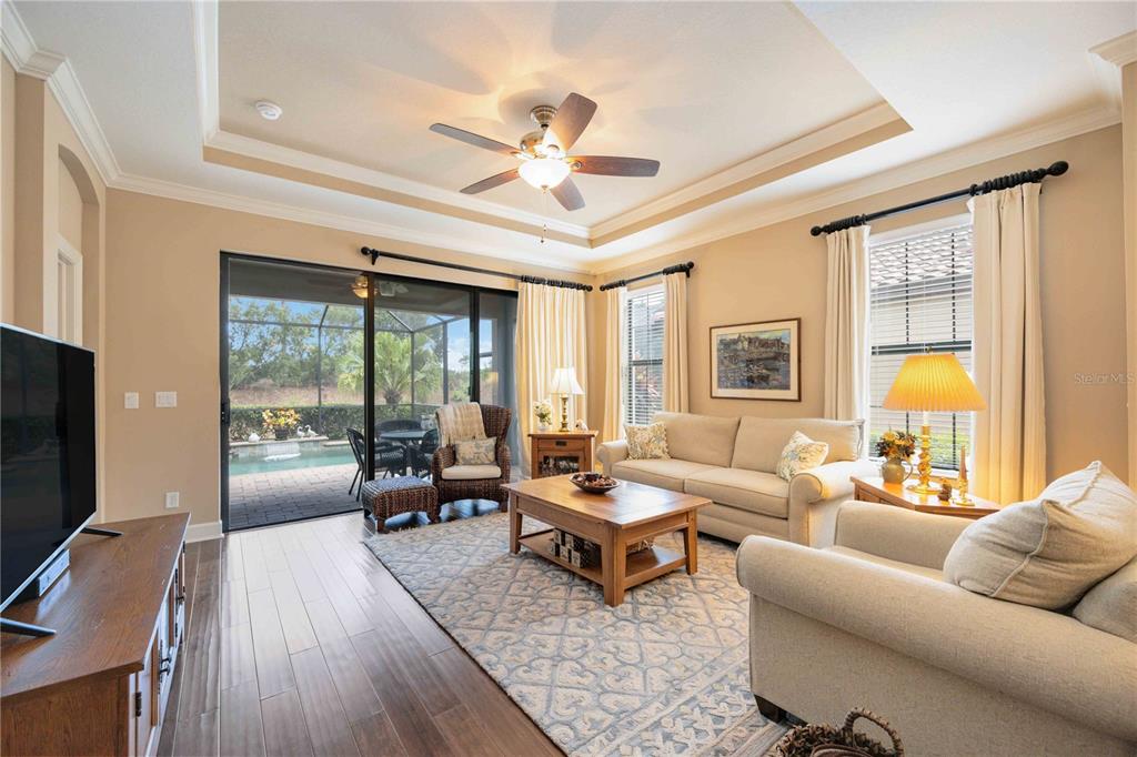 13202 Torresina Terrace Lakewood Ranch, FL 34211 - Photo 6 of 35 a living room with furniture a flat screen tv and a floor to ceiling window