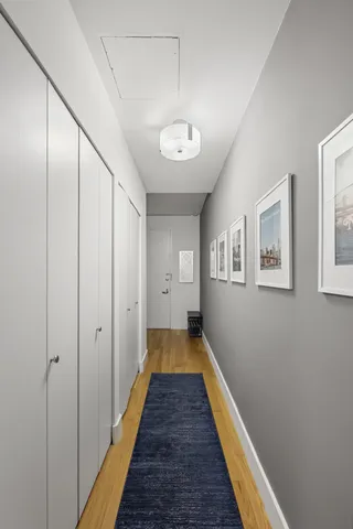 a view of a hallway with wooden floor and a bathroom