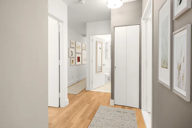 a view of a hallway with wooden floor and closet