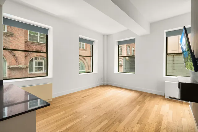 a view of an empty room with a window and wooden floor