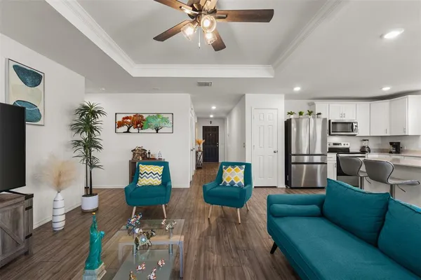 a living room with furniture kitchen view and a wooden floor