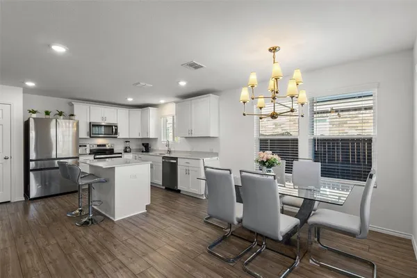 a kitchen with a dining table chairs appliances and cabinets