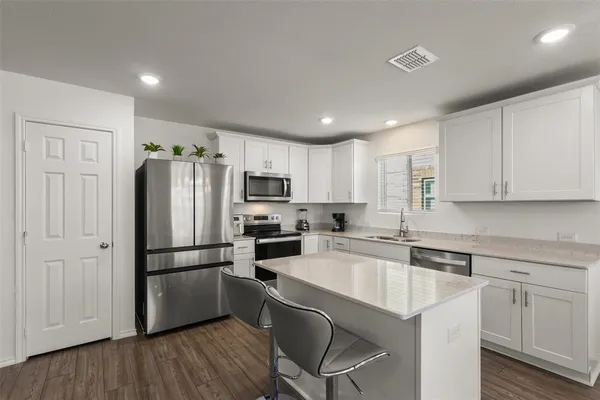 a kitchen with white cabinets and stainless steel appliances