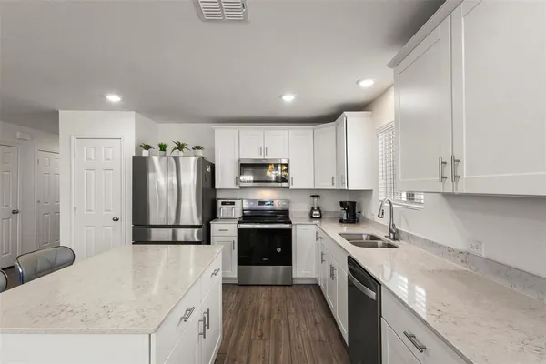 a kitchen with granite countertop a refrigerator a sink a stove a microwave and island