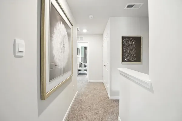 a view of a hallway with wooden floor and a bathroom
