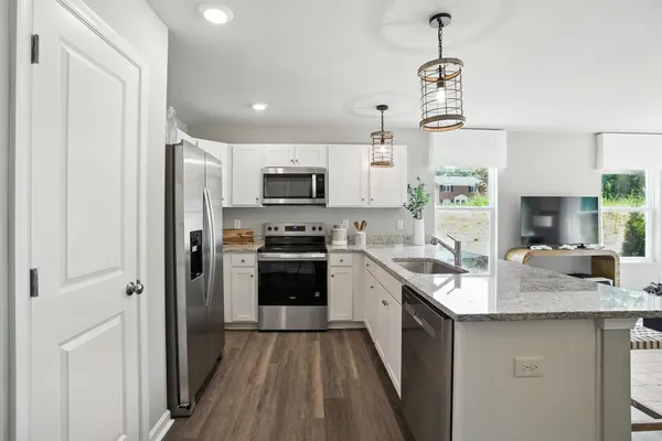 a kitchen with kitchen island granite countertop stainless steel appliances a sink a stove a refrigerator cabinets and a window