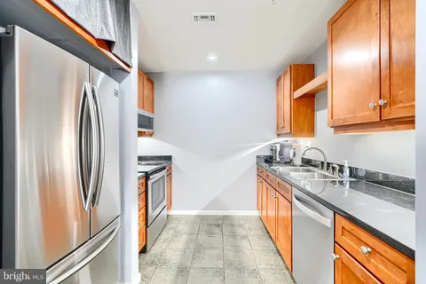 a kitchen with stainless steel appliances granite countertop a refrigerator a stove and a sink