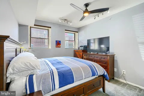 a bedroom with a bed a chandelier and dresser