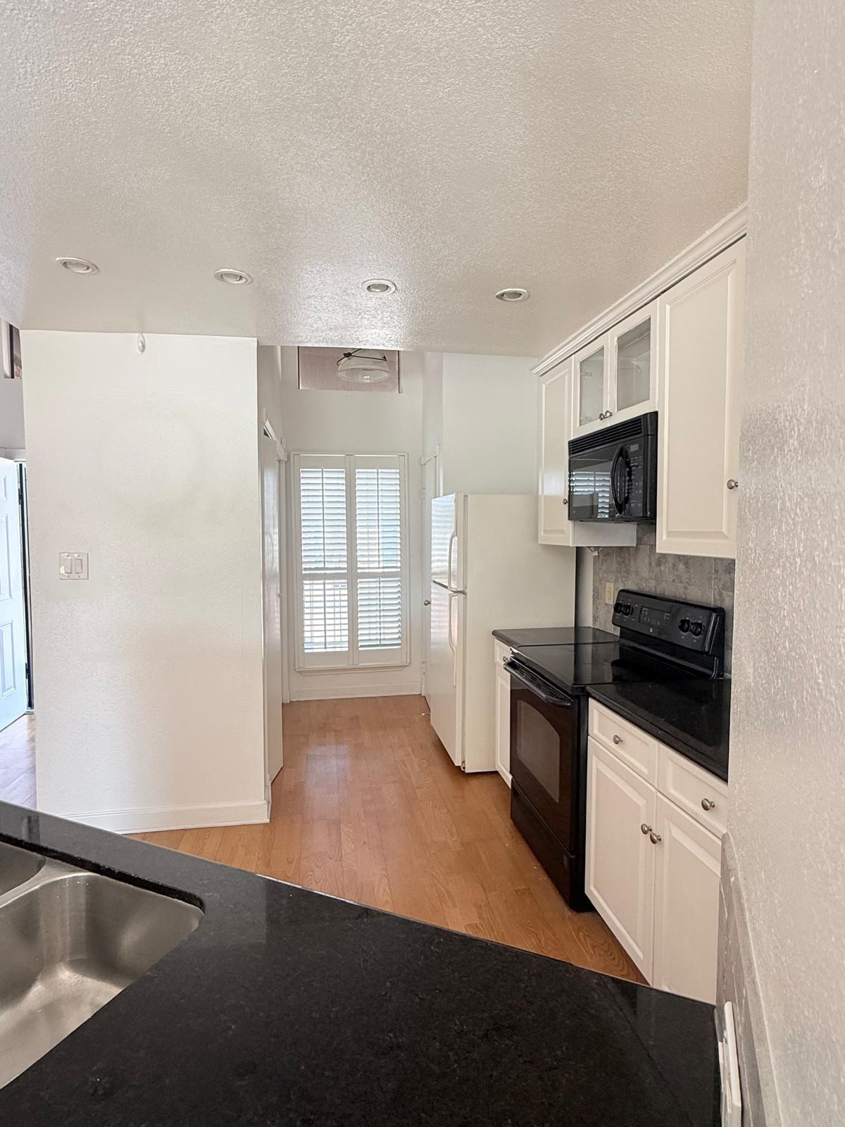 8287 Sands Point Drive, Unit 128 Houston, TX 77036 - Photo 7 of 30 a kitchen with granite countertop a refrigerator a sink a stove a microwave a counter top space and cabinets