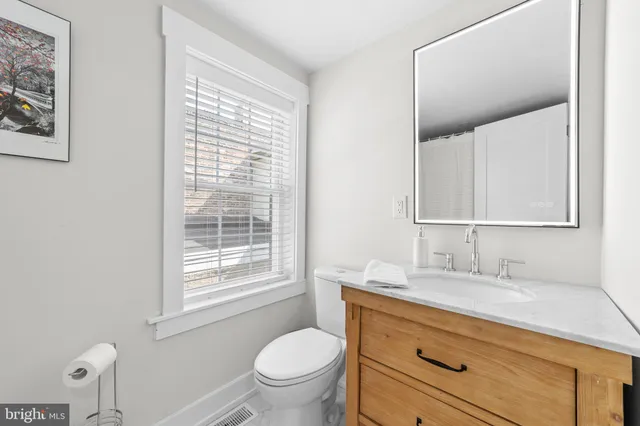 a bathroom with a granite countertop toilet sink and mirror