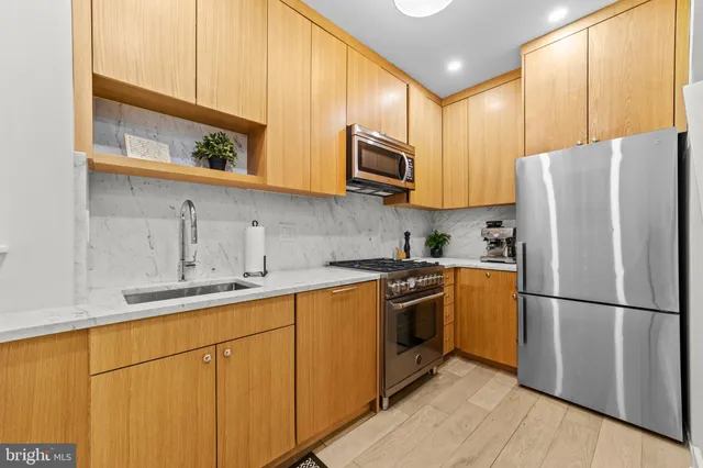 a kitchen with stainless steel appliances granite countertop a refrigerator stove a sink and dishwasher with wooden floor