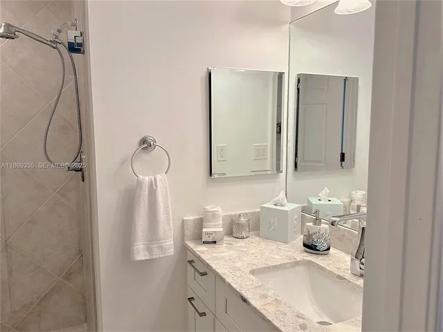a bathroom with a granite countertop sink a shower and a mirror
