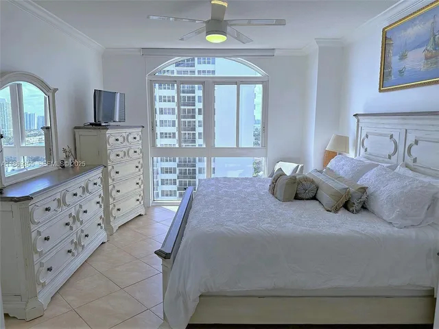 a bedroom with a bed a mirror on dresser and a chandelier