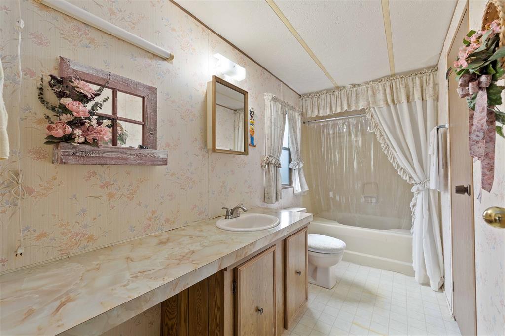 11814 County Road 266 Rochelle, TX 76872 - Photo 30 of 40 a bathroom with a granite countertop sink a toilet a large mirror a vanity and shower