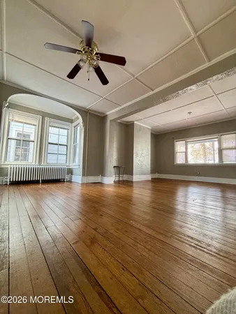 a view of empty room with wooden floor and fan