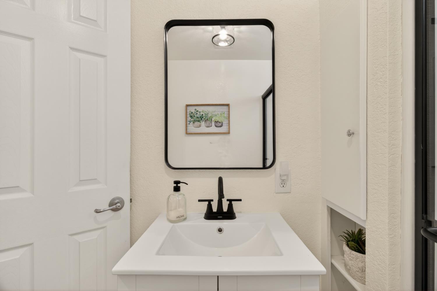 6332 Horseshoe Bar Road Loomis, CA 95650 - Photo 22 of 85 White vanity with an integrated sink and matte black faucet, featuring a framed rectangular mirror