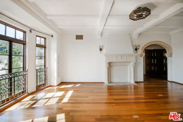 a view of an empty room with window and wooden floor