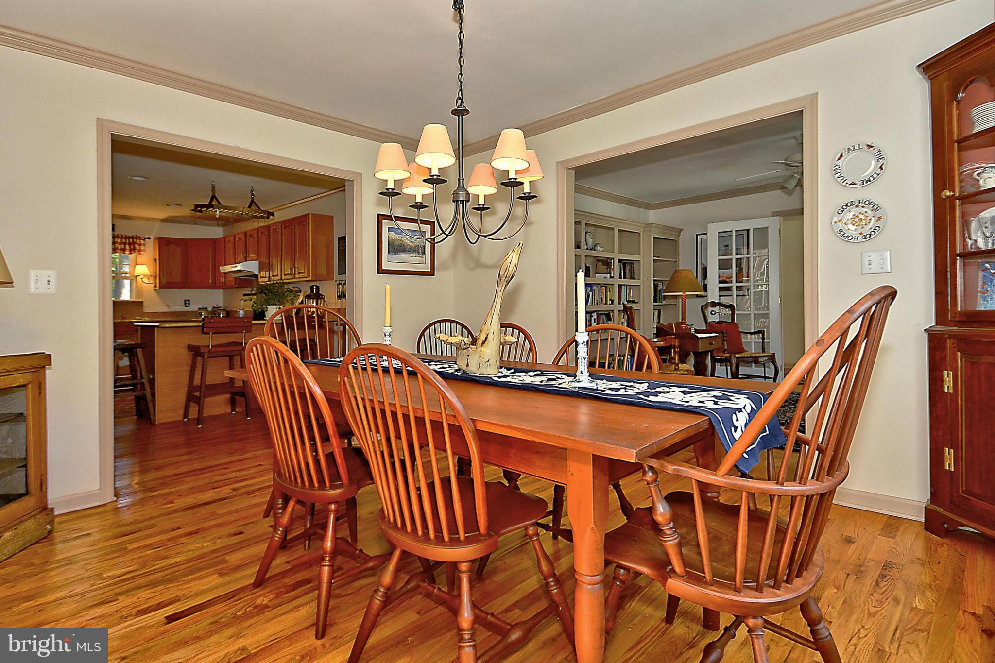 24100 Forest Pond Road St. Michaels, MD 21663 - Photo 8 of 20 a dining room with furniture a chandelier and wooden floor