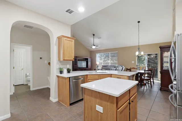 a kitchen with a stove a refrigerator a dining table and chairs with the view of living room