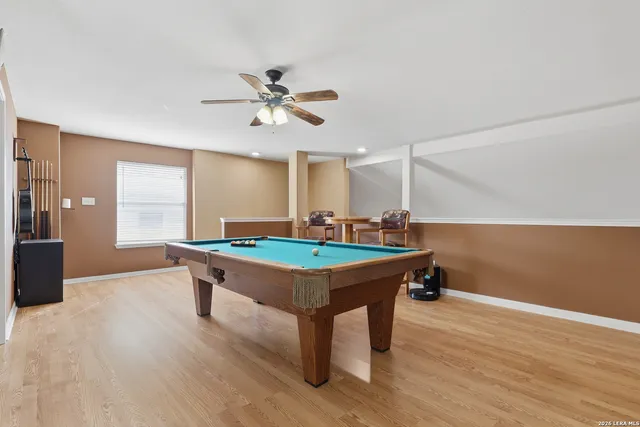 a room with wooden floor pool table and windows