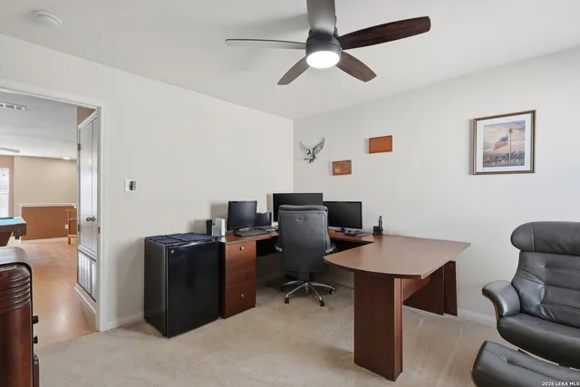 a view of a workspace with furniture and a ceiling fan