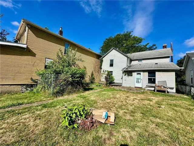 a view of a white house with a big yard and sitting area