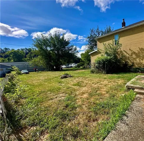a view of a large pool with lawn chairs under an umbrella