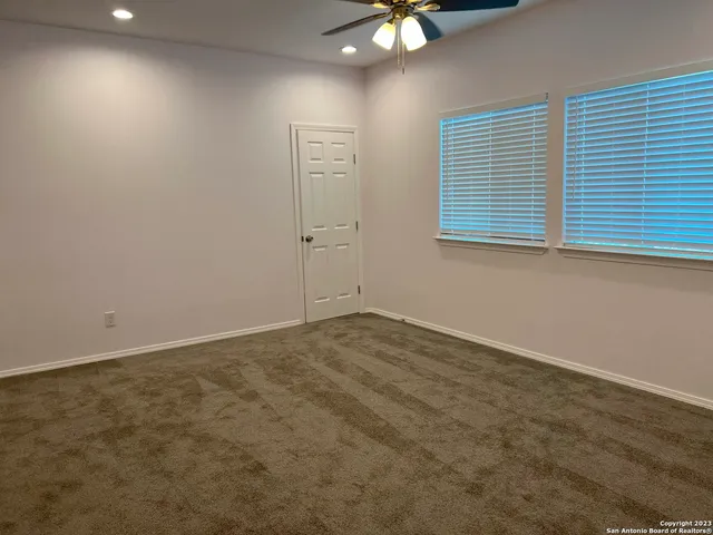 an empty room with a chandelier fan and windows