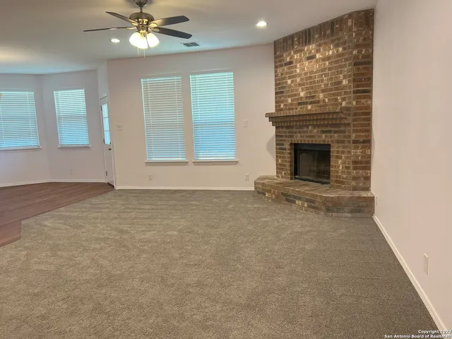 a view of an empty room with a fireplace and a window