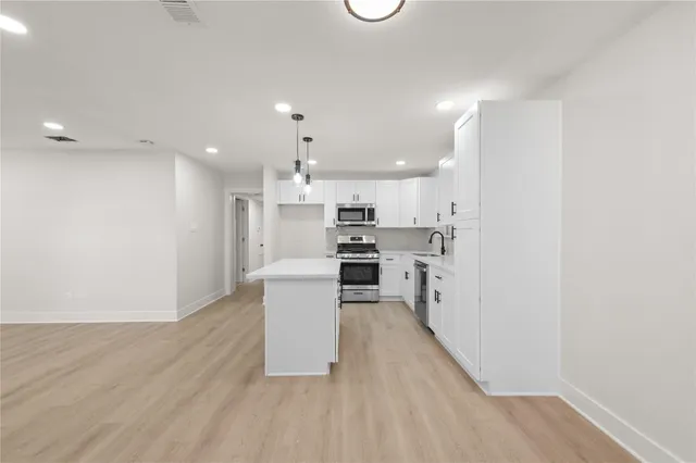a kitchen with kitchen island white cabinets and stainless steel appliances