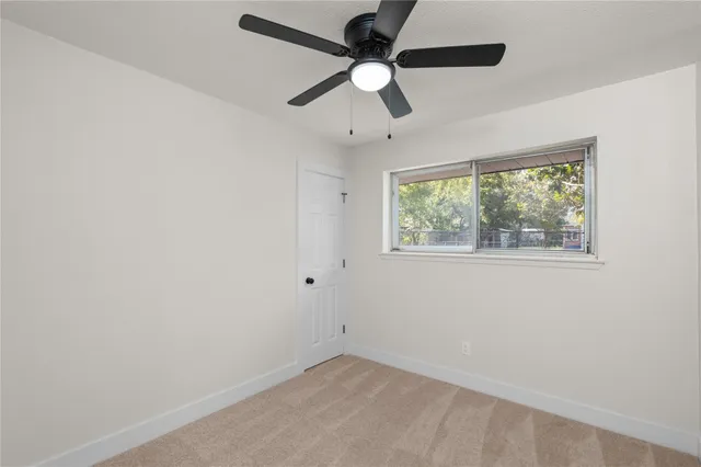 an empty room with a window and a fan