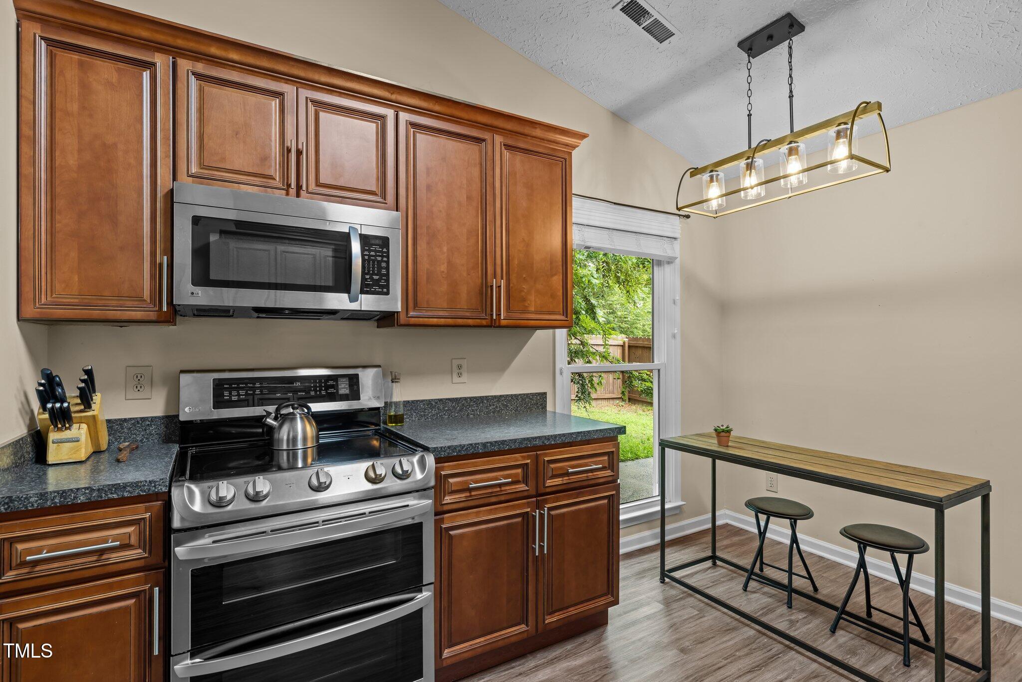 5801 Hadrian Drive Durham, NC 27703 - Photo 11 of 40 a kitchen with stainless steel appliances granite countertop a stove microwave and refrigerator