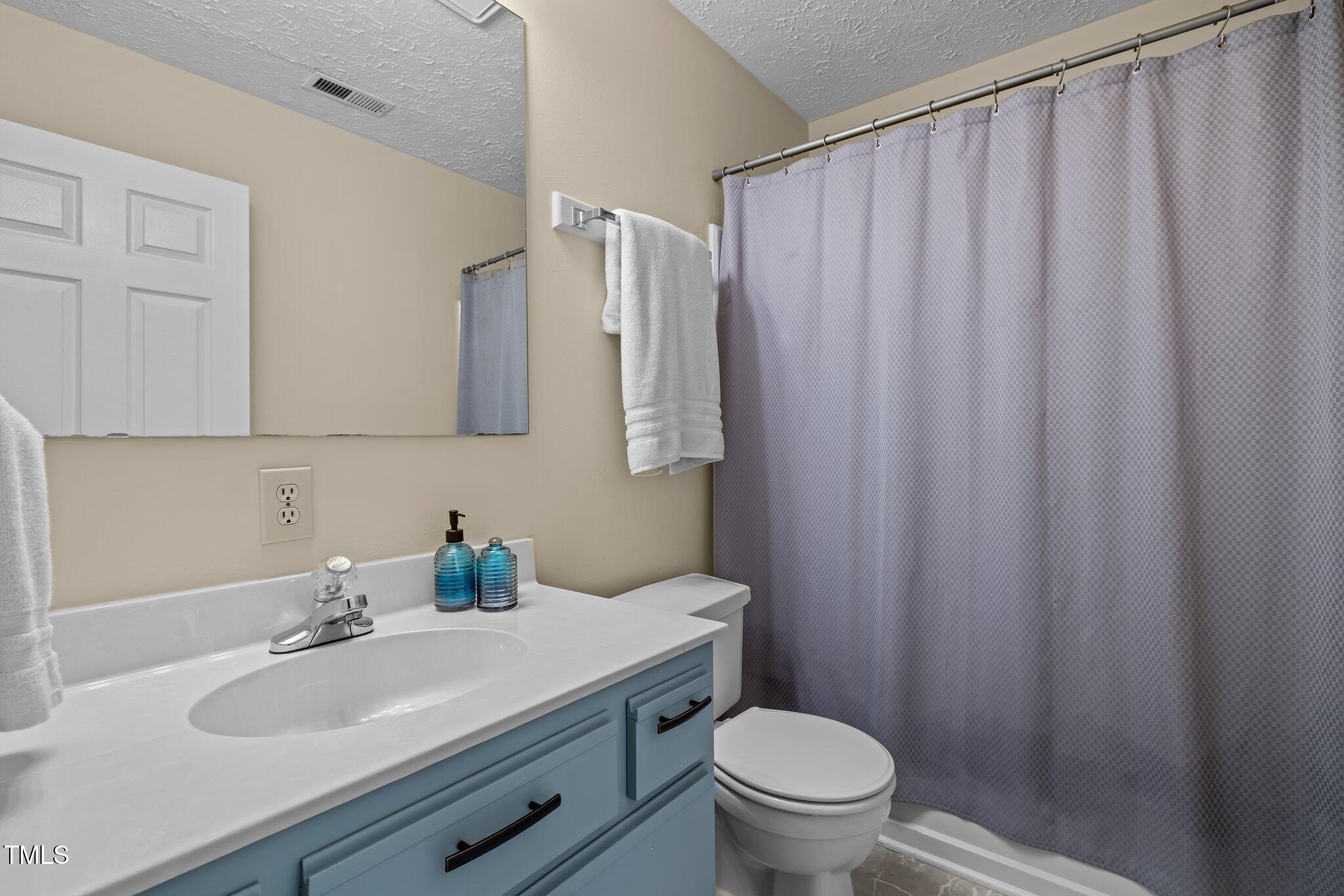 5801 Hadrian Drive Durham, NC 27703 - Photo 20 of 40 a bathroom with a sink a toilet and shower curtain
