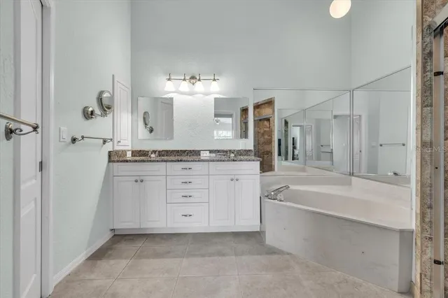 a bathroom with a granite countertop bathtub shower sink vanity and toilet
