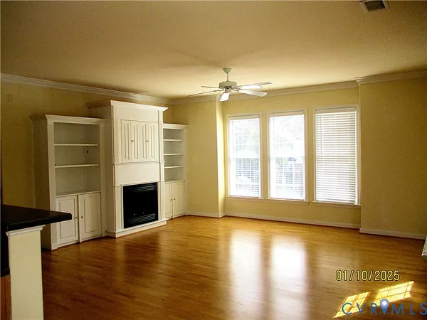 a view of an empty room with a fireplace and wooden floor
