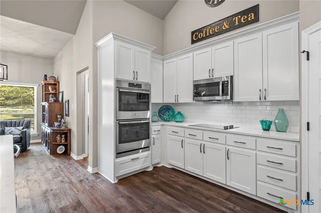 a kitchen with white cabinets stainless steel appliances and wooden floor