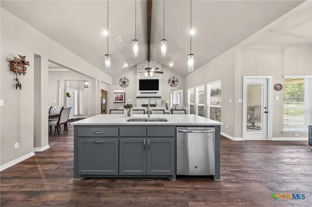 a kitchen with kitchen island granite countertop a sink cabinets and stainless steel appliances
