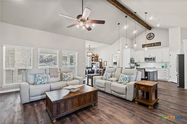 a living room with furniture kitchen view and a chandelier