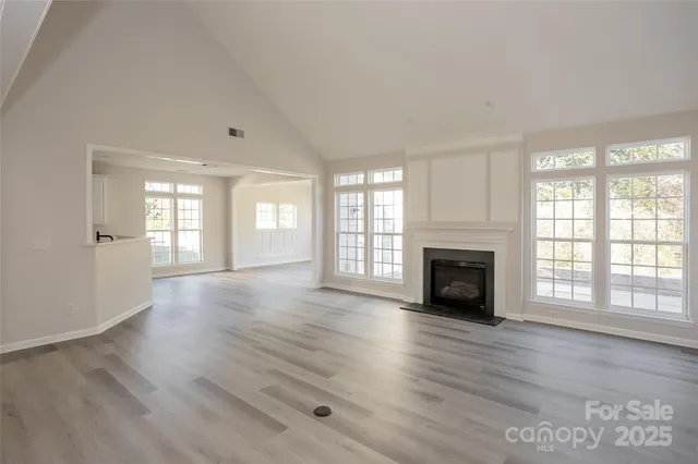 an empty room with windows fireplace and wooden floor